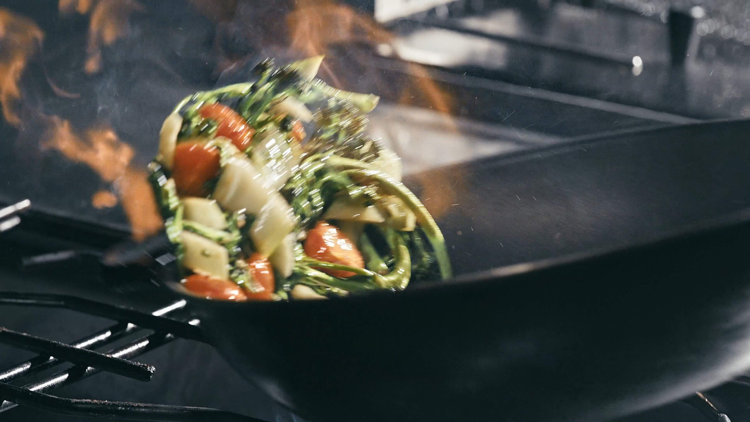 Brennender Wok in dem Gemüse geschwenkt wird