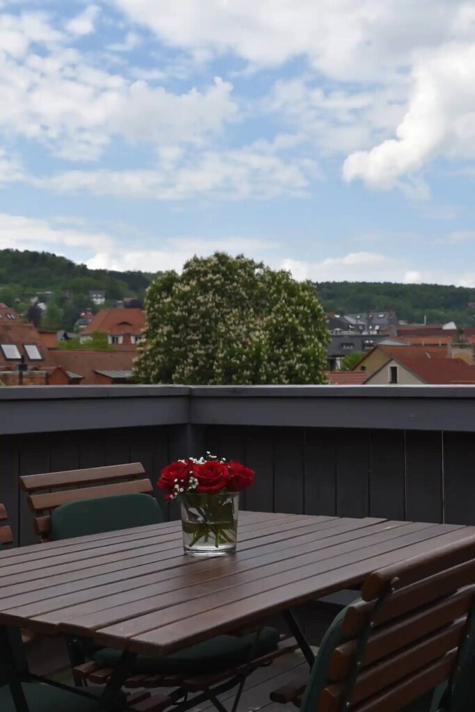 Balkon mit Holztisch mit einer Blumenvase